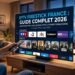 Man relaxing on a sofa with a remote, watching a smart TV displaying a French IPTV guide with channel icons and movie thumbnails.